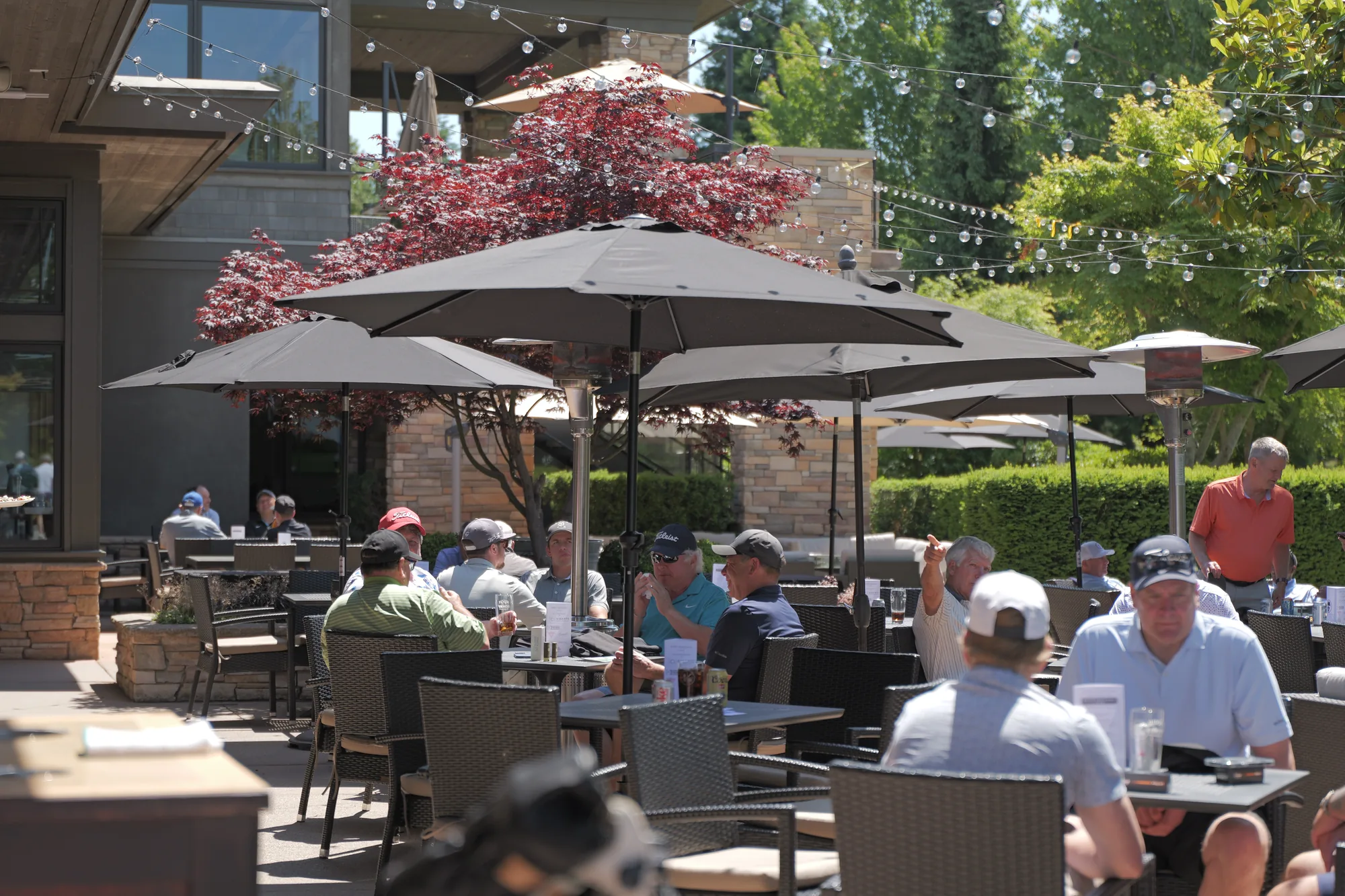 Members at tables on the Beach Grove Golf Club patio after a round